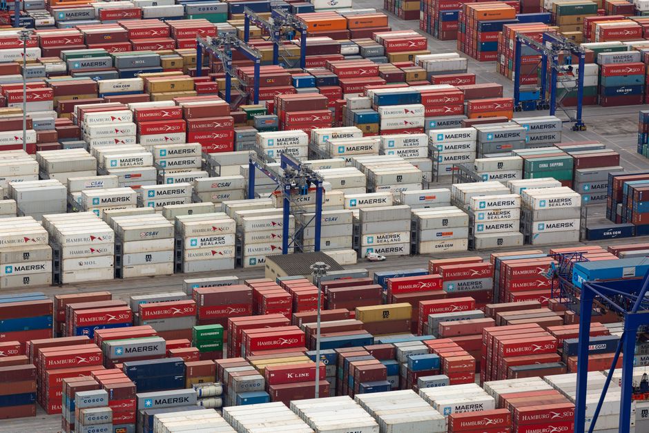 Aerial view of a bustling port with colorful cargo containers arranged in rows, showcasing logistics and trade.